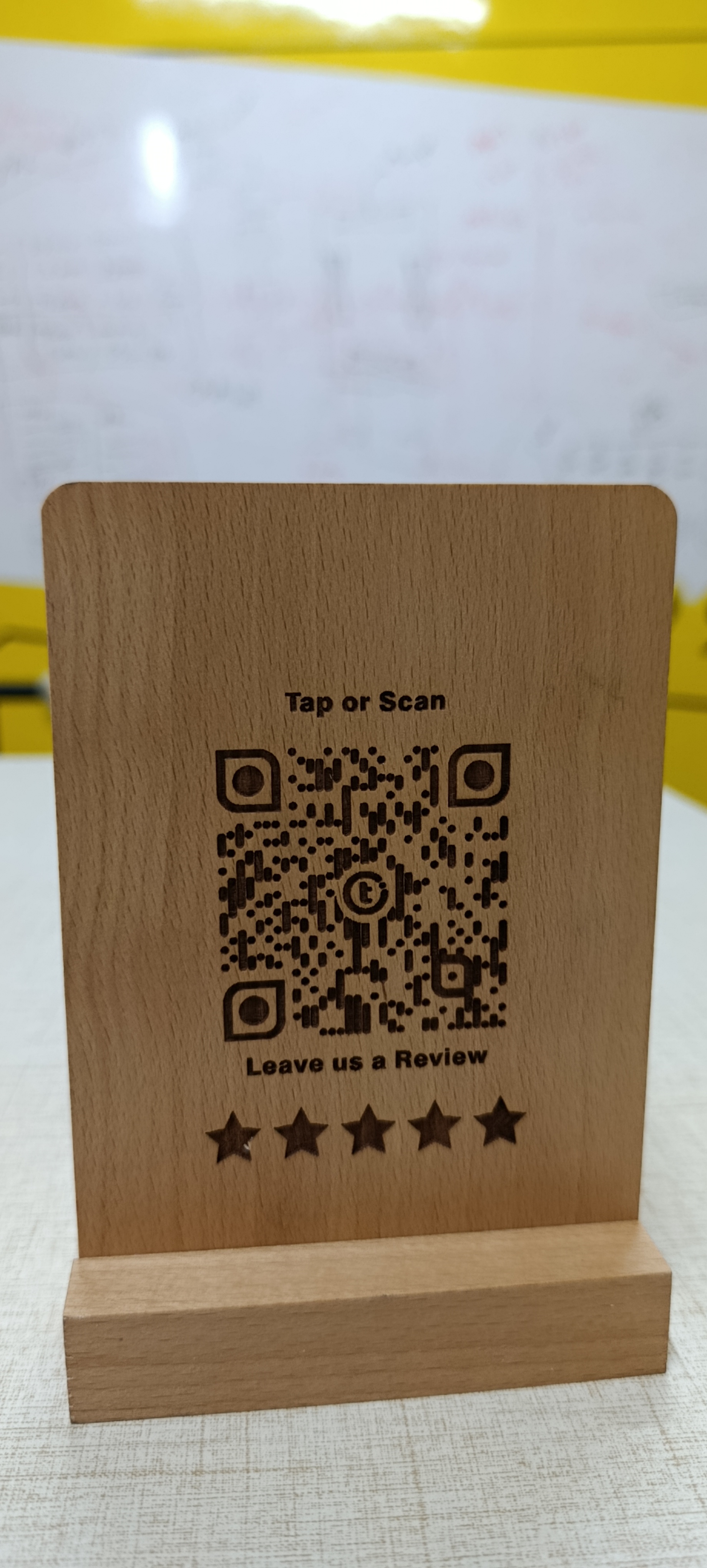 Close-up of the Review+ beechwood standee showing high-density laser-engraved QR detail and engraved stars